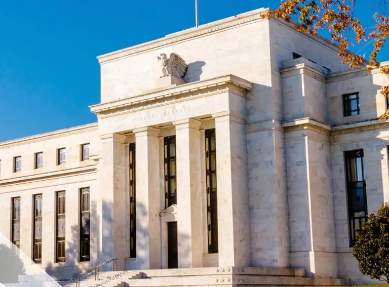 A large, white stone building with columns and an eagle sculpture above the entrance, set against a clear blue sky with some autumn leaves in the foreground—an iconic setting where you’ll want to avoid losing an ATO.