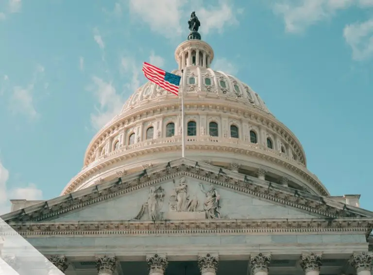 The United States Capitol building with its dome and an American flag waving in the foreground, set against a clear blue sky, symbolizes the nation’s commitment to security and transparency—values reflected in StateRAMP compliance.